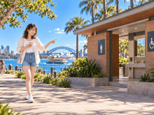 シドニーの公園でスマホを手に公衆トイレの場所を確かめる日本人留学生。オーストラリアの公衆トイレ探し
